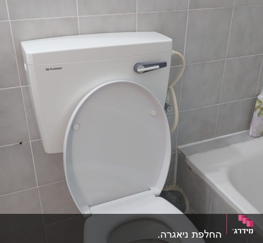 אסלה לבנה מותקנת בחדר אמבטיה עם אריחים אפורים